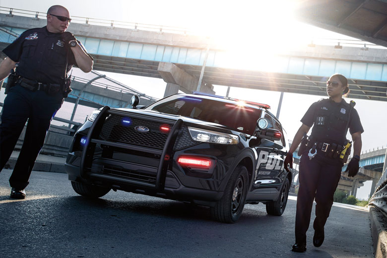 Two cops walking in front of a cop car